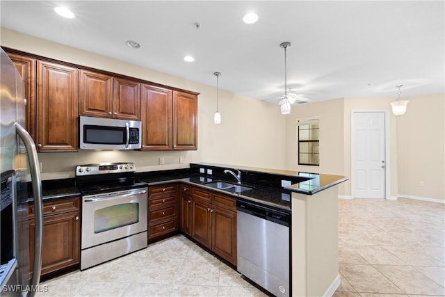 kitchen with decorative light fixtures, sink, kitchen peninsula, and stainless steel appliances