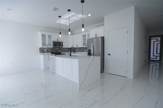 kitchen featuring decorative light fixtures, an island with sink, white cabinets, stainless steel appliances, and light stone countertops