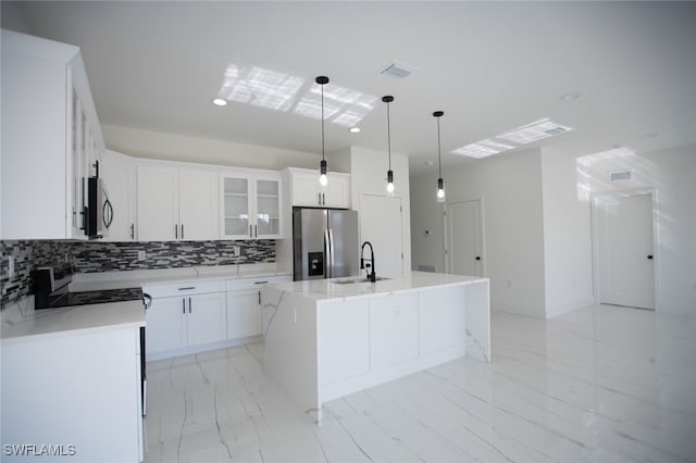 kitchen featuring sink, stainless steel appliances, white cabinets, a center island with sink, and decorative light fixtures