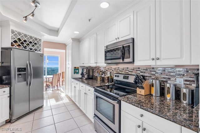 kitchen with white cabinetry, light tile patterned floors, stainless steel appliances, and dark stone countertops