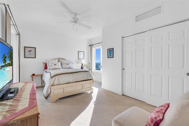 bedroom featuring ceiling fan, a closet, and light colored carpet