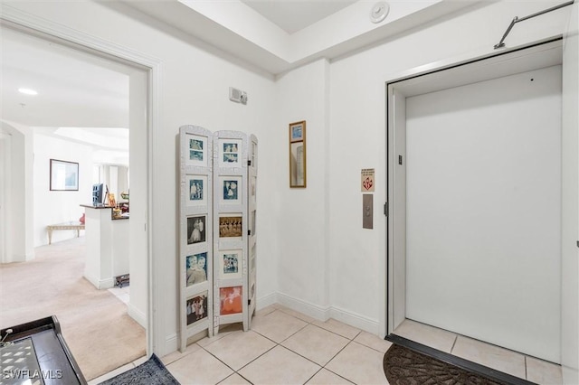 hall featuring light tile patterned flooring and elevator