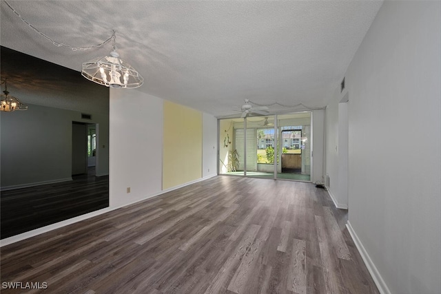 spare room with a textured ceiling, hardwood / wood-style floors, and a notable chandelier