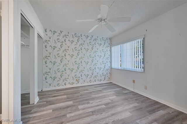 unfurnished bedroom featuring a closet, ceiling fan, light hardwood / wood-style floors, and a textured ceiling