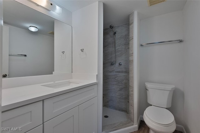 bathroom with tiled shower, toilet, and vanity