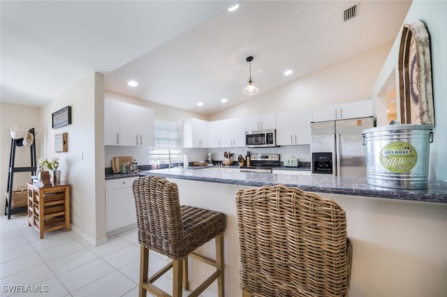 kitchen featuring appliances with stainless steel finishes, light tile patterned floors, hanging light fixtures, and white cabinets