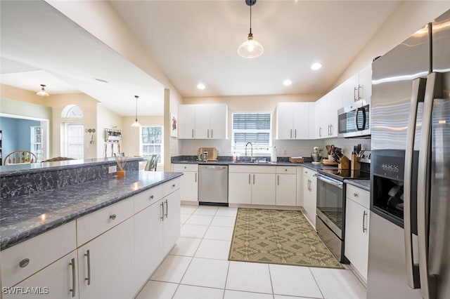 kitchen with sink, white cabinets, hanging light fixtures, light tile patterned floors, and stainless steel appliances