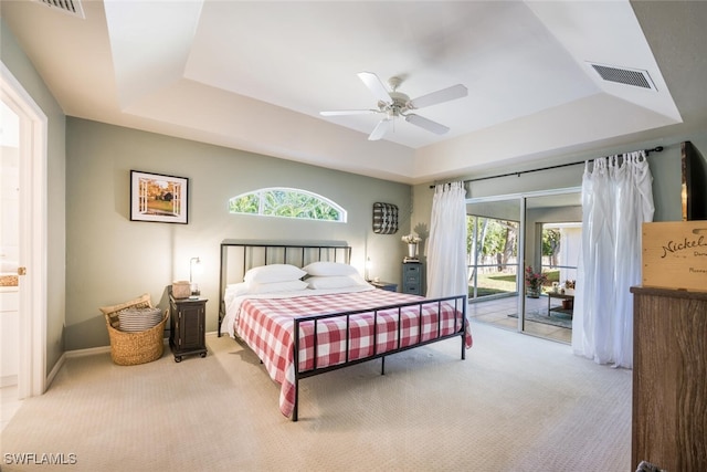 carpeted bedroom with multiple windows, access to outside, and a raised ceiling