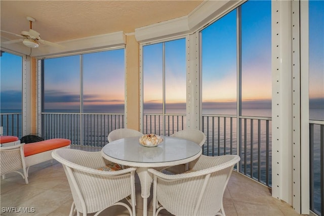 sunroom featuring ceiling fan and a water view