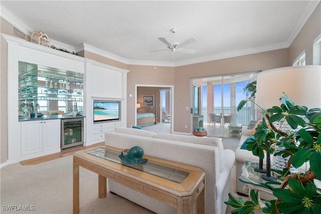 living room featuring ceiling fan, bar area, ornamental molding, and beverage cooler