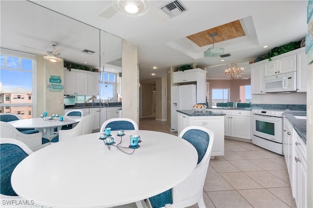 kitchen featuring white appliances, white cabinets, a center island, and hanging light fixtures