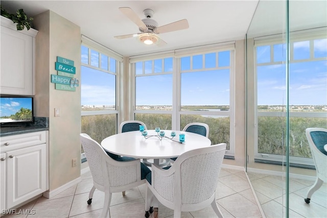 dining area featuring ceiling fan, light tile patterned floors, and a wall of windows