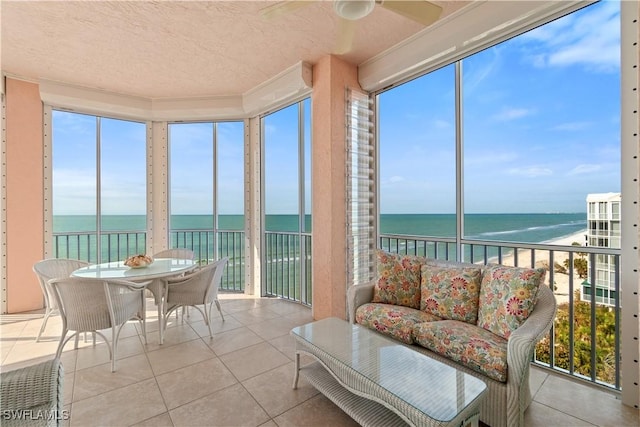 sunroom featuring a water view and a beach view