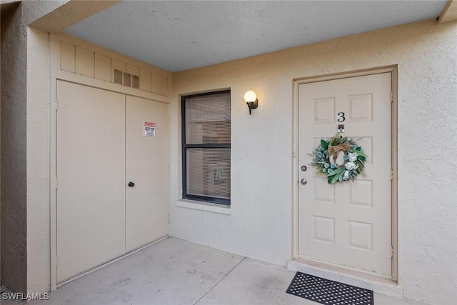 doorway to property featuring stucco siding