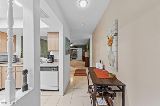 interior space featuring light tile patterned floors, white dishwasher, light brown cabinets, visible vents, and light countertops