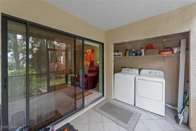 laundry area with a textured wall, laundry area, washing machine and clothes dryer, and tile patterned floors