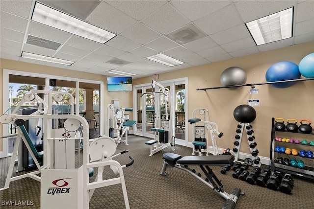 exercise room featuring french doors, a paneled ceiling, and carpet