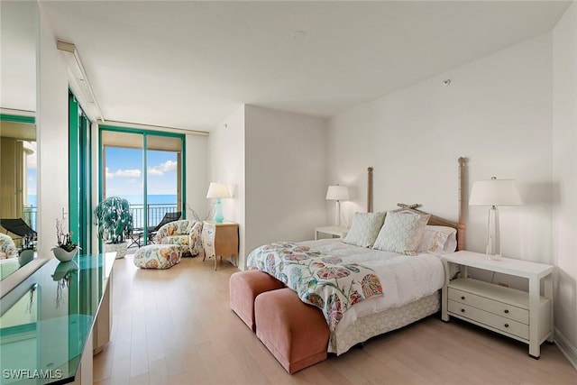 bedroom featuring light wood-type flooring, expansive windows, and access to outside