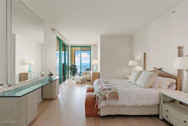 bedroom with light hardwood / wood-style floors, floor to ceiling windows, and access to outside