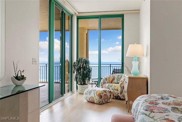 bedroom with multiple windows, a wall of windows, and a water view