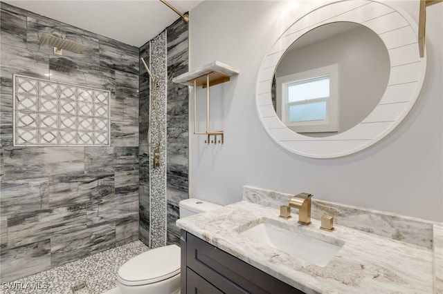 bathroom featuring vanity, tiled shower, and toilet