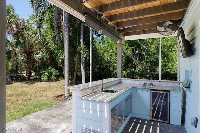 view of patio / terrace featuring wine cooler, ceiling fan, exterior kitchen, and sink