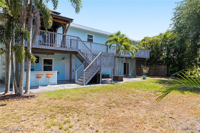 back of property with a wooden deck, a patio, and a lawn