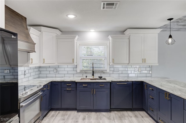 kitchen featuring white cabinetry, blue cabinetry, electric stove, and sink