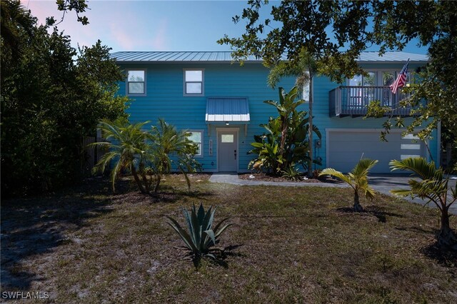 view of front of house with a balcony, a garage, and a lawn