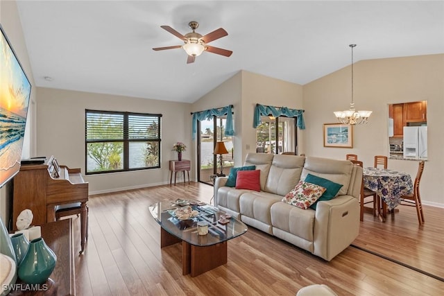 living room with vaulted ceiling, ceiling fan with notable chandelier, and light hardwood / wood-style floors