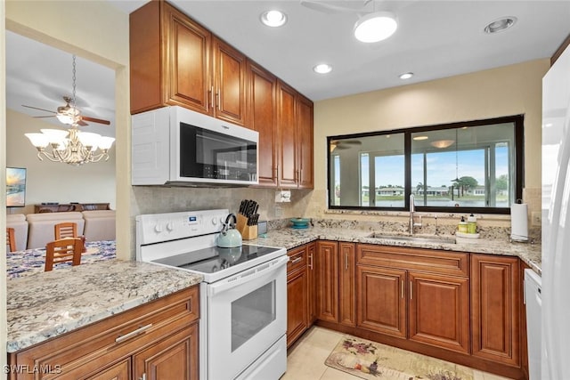 kitchen featuring light stone counters, white appliances, light tile patterned flooring, and sink