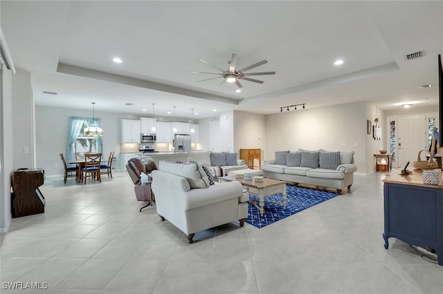 living room with ceiling fan, track lighting, and a raised ceiling