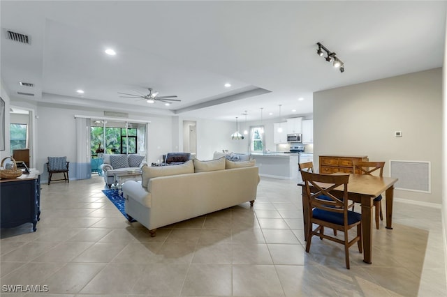 living room with plenty of natural light, a raised ceiling, and light tile patterned flooring