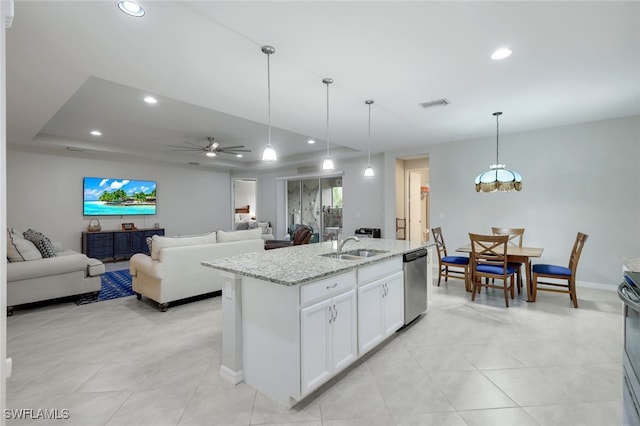 kitchen with hanging light fixtures, white cabinets, stainless steel appliances, light stone counters, and a center island with sink