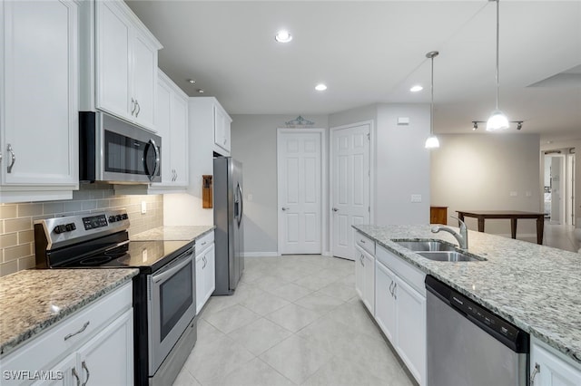 kitchen with hanging light fixtures, sink, white cabinets, light stone countertops, and stainless steel appliances