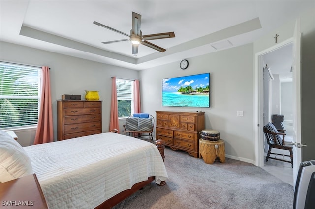 carpeted bedroom featuring ceiling fan and a raised ceiling