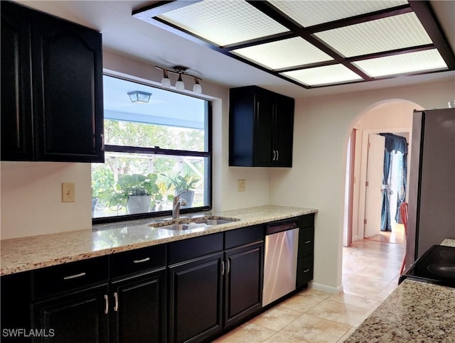 kitchen featuring light stone counters, sink, light tile patterned floors, and appliances with stainless steel finishes