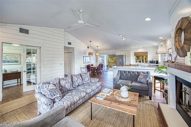 living room featuring ceiling fan, dark hardwood / wood-style floors, wood walls, and vaulted ceiling