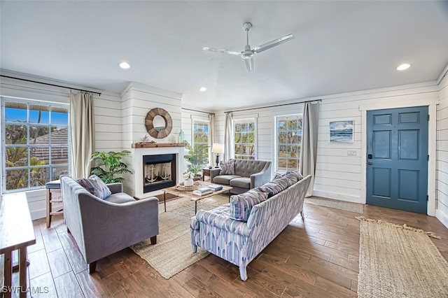 living room featuring ceiling fan, dark hardwood / wood-style flooring, and wood walls