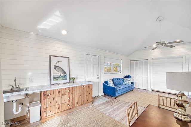 sitting room featuring vaulted ceiling, sink, wood walls, and light hardwood / wood-style flooring