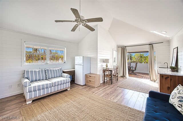 living room featuring ceiling fan, light hardwood / wood-style flooring, and vaulted ceiling