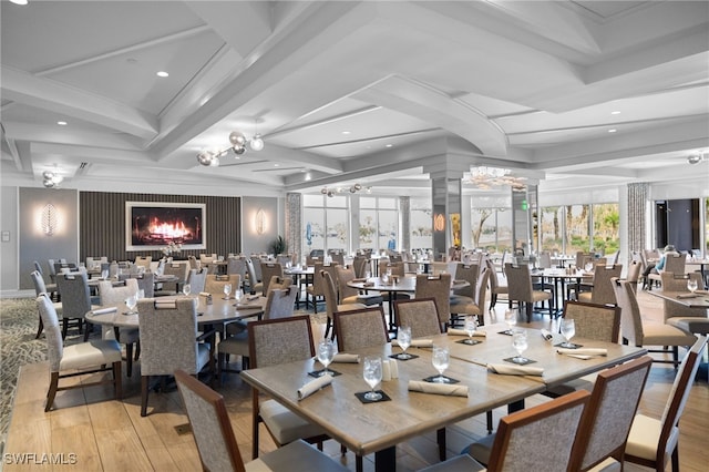 dining room featuring ornate columns, a healthy amount of sunlight, light wood-type flooring, and beamed ceiling