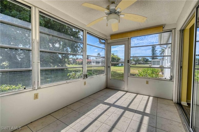 unfurnished sunroom featuring ceiling fan and plenty of natural light