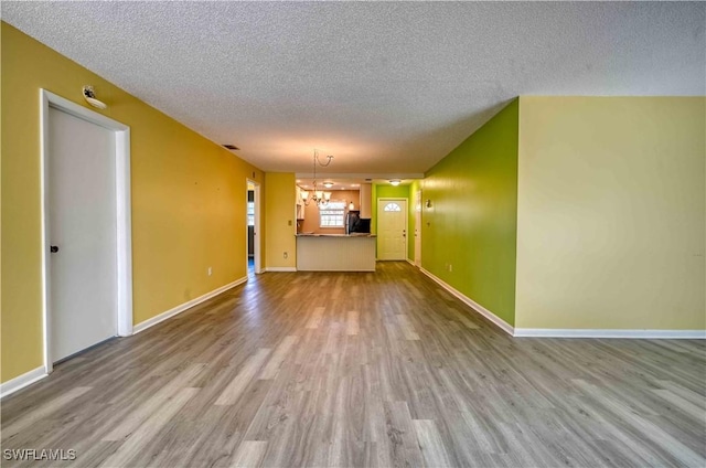 unfurnished living room with a textured ceiling, light hardwood / wood-style floors, and a chandelier