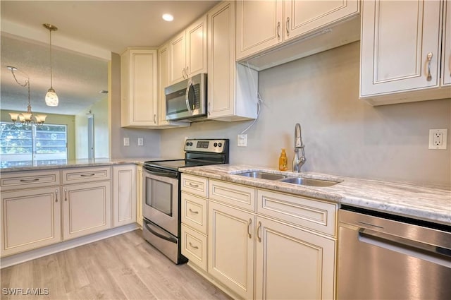 kitchen featuring sink, stainless steel appliances, light stone counters, light hardwood / wood-style floors, and decorative light fixtures