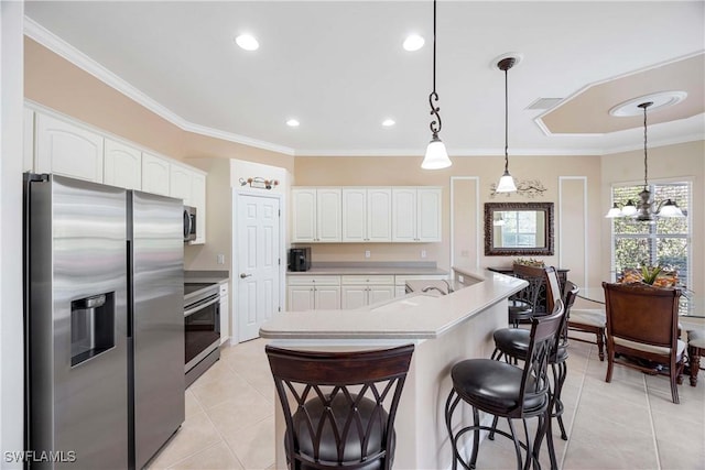 kitchen featuring light tile patterned floors, appliances with stainless steel finishes, white cabinetry, hanging light fixtures, and a kitchen breakfast bar