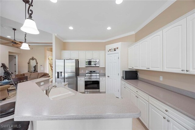 kitchen featuring sink, crown molding, hanging light fixtures, stainless steel appliances, and white cabinets