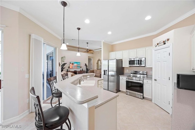 kitchen with hanging light fixtures, light tile patterned floors, appliances with stainless steel finishes, a kitchen island with sink, and white cabinets