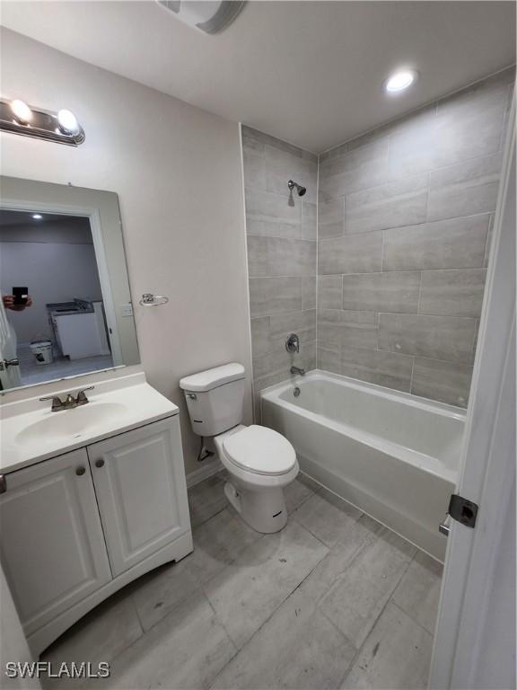 full bathroom with tiled shower / bath combo, vanity, and toilet