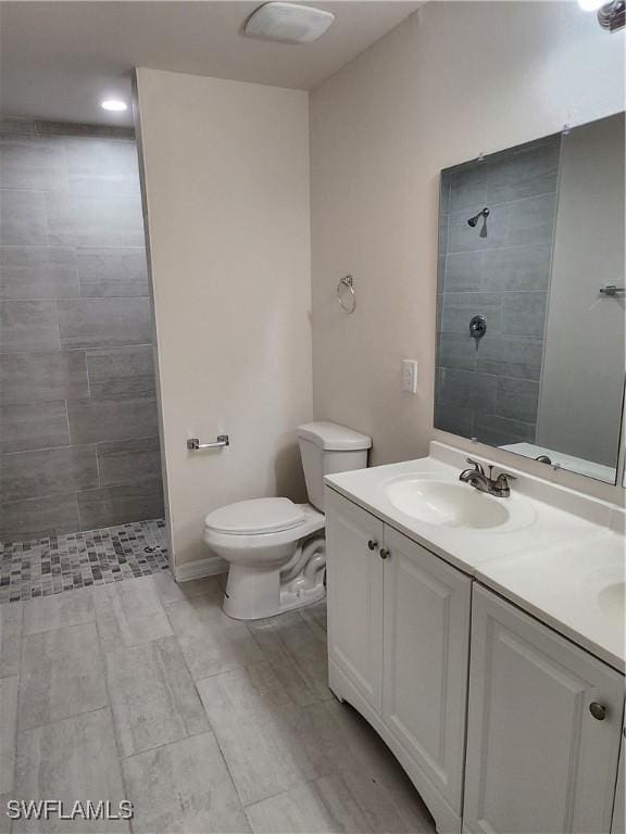 bathroom featuring toilet, vanity, and tiled shower